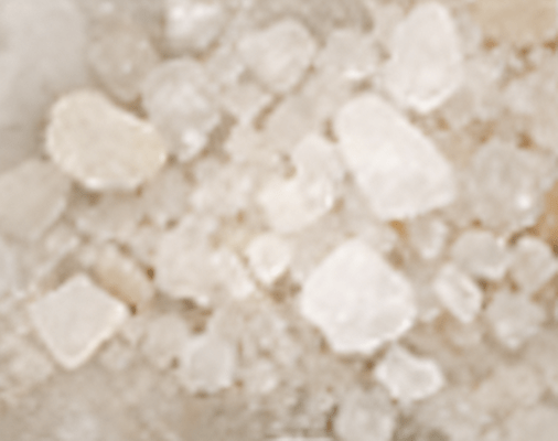 Close-up of coarse sea salt crystals scattered randomly.